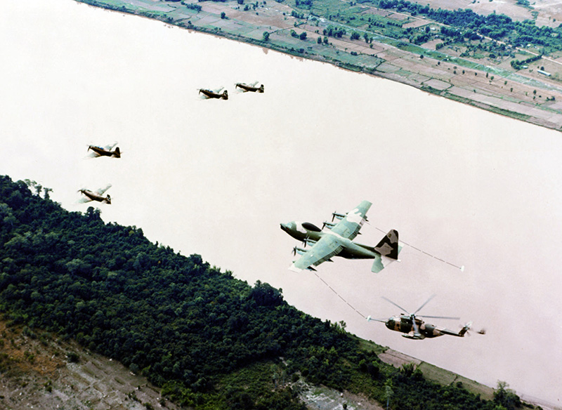 U.S. Air Force air rescue team Four NKP based A-1 Skyraiders and a Lockheed HC-130P Hercules recovery aircraft refueling a Sikorsky HH-3E Jolly Green Giant helicopter