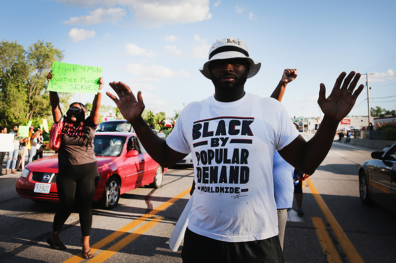 FERGUSON, MO - AUGUST 12: Demonstrators protest the killing of teenager Michael Brown on August 12, 2014 in Ferguson, Missouri. Brown was shot and killed by a police officer on Saturday in the St. Louis suburb of Ferguson. Ferguson has experienced two days of violent protests since the killing but, tonight's protest was peaceful. (Photo by Scott Olson/Getty Images)