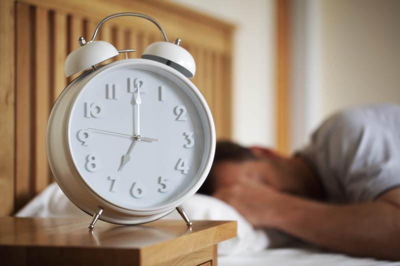 Man sleeping with alarm clock foreground concept for morning, time to wake up or fatigue