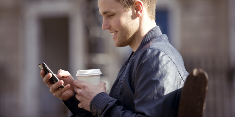 A young man sitting on a bench, using his mobile phone