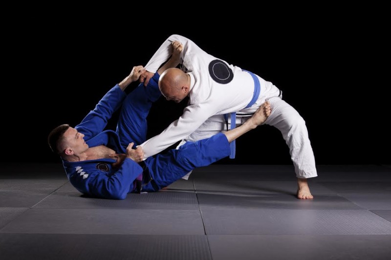 Two jiujitsu wrestlers sparring in combat during the sport training. One fighter lying on the floor mat and second one is standing.Brazilian jiu-jitsu is martial art similar to judo, and mostly is focused on ground fighting.
