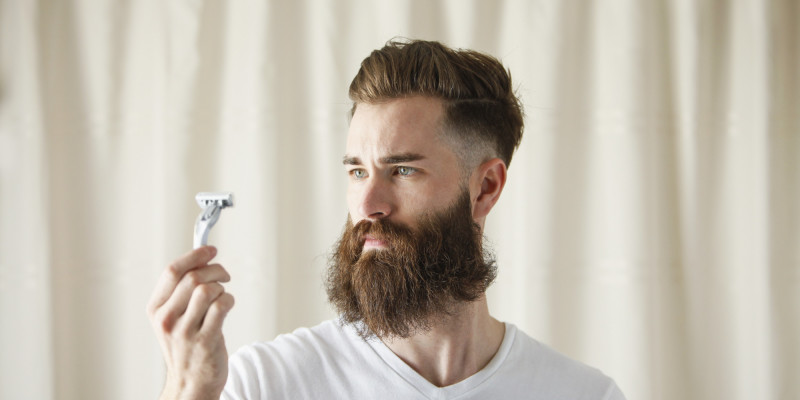 Bearded Caucasian man examining razor