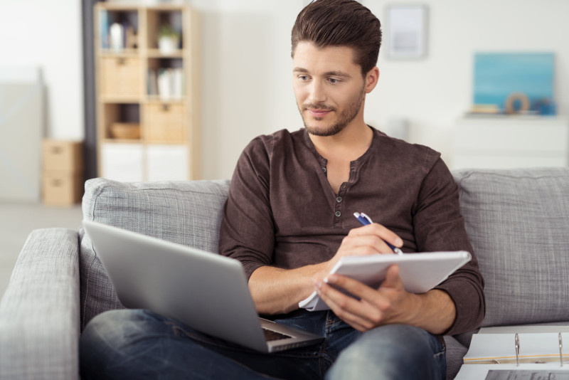 mann mit laptop und unterlagen in seiner wohnung