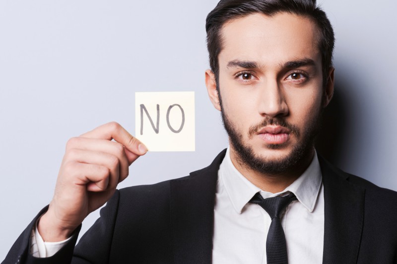 I said No. Handsome young man in formalwear holding adhesive note while standing against grey background